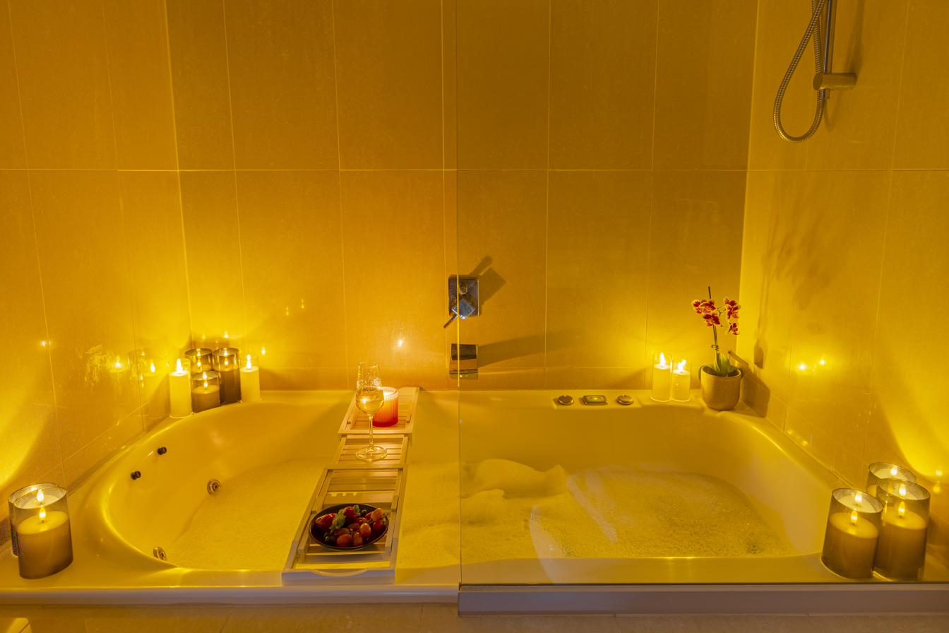 Candle-lit bubble bath with orchid