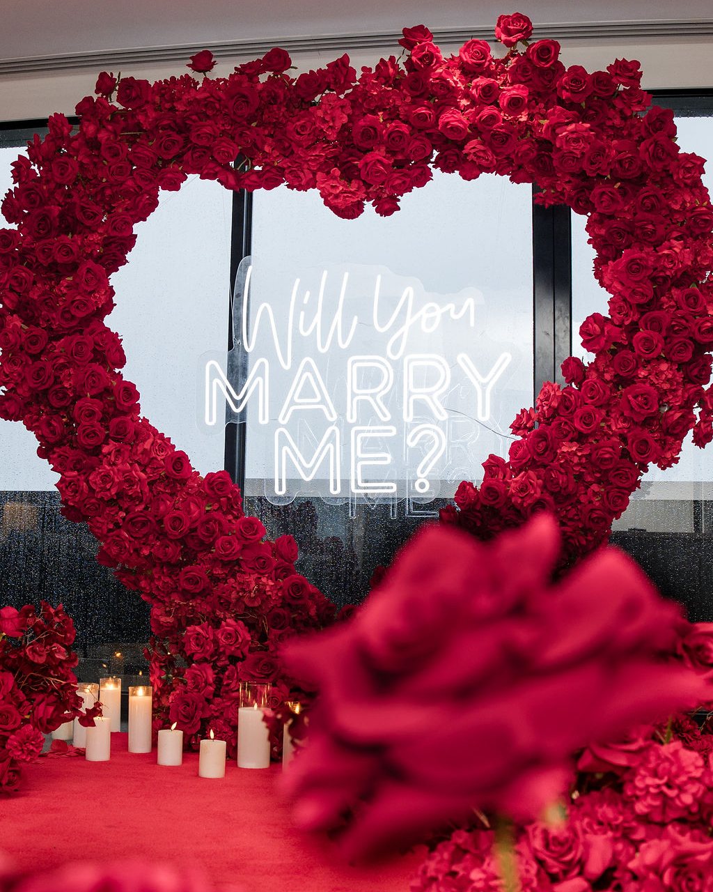 Rose heart arch framing a Will You Marry Me neon sign in the penthouse
